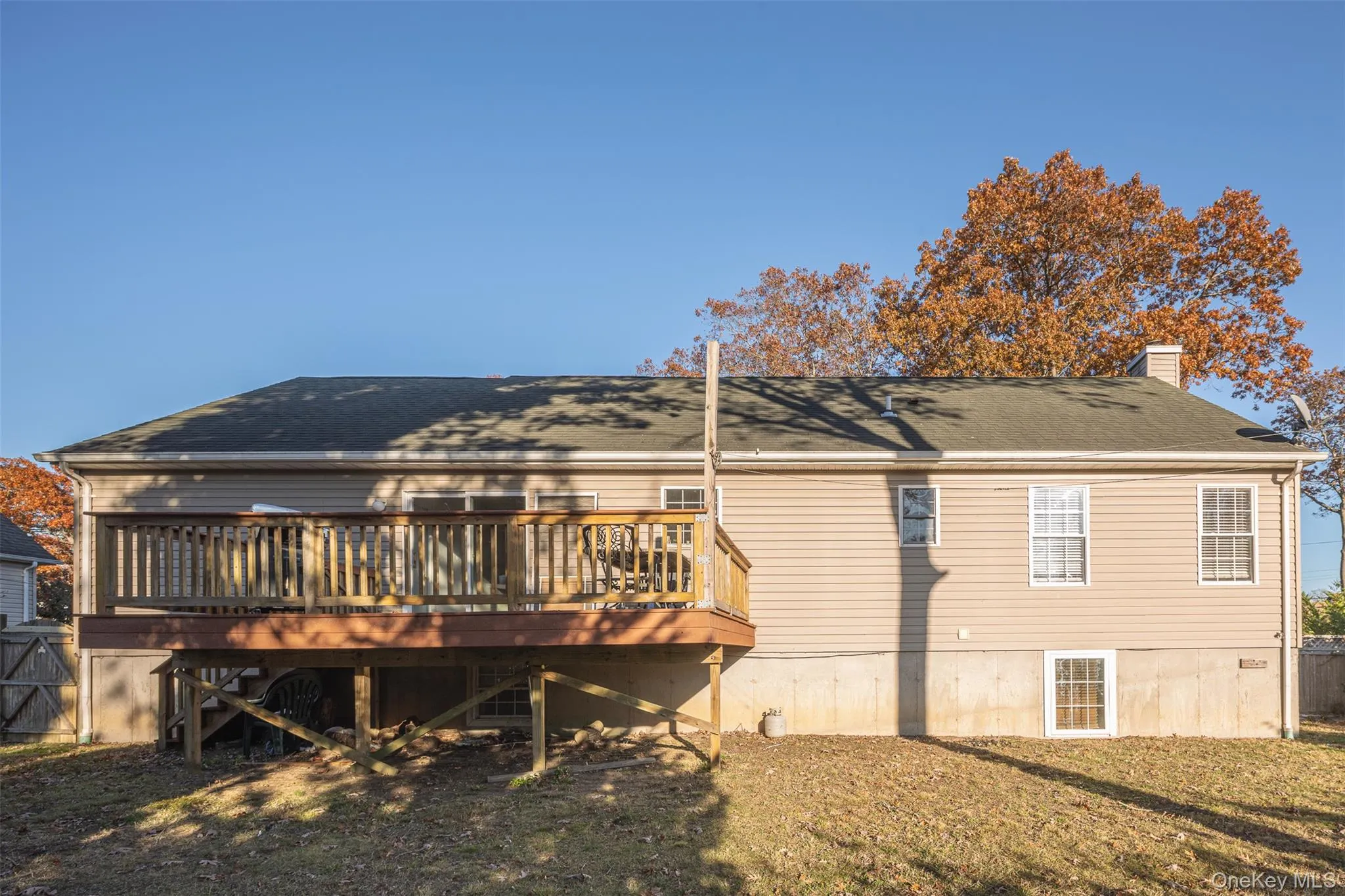 Back of property with a chimney, a wooden deck, and roof with shingles Back of property with a chimney, a wooden deck, and roof with shingles