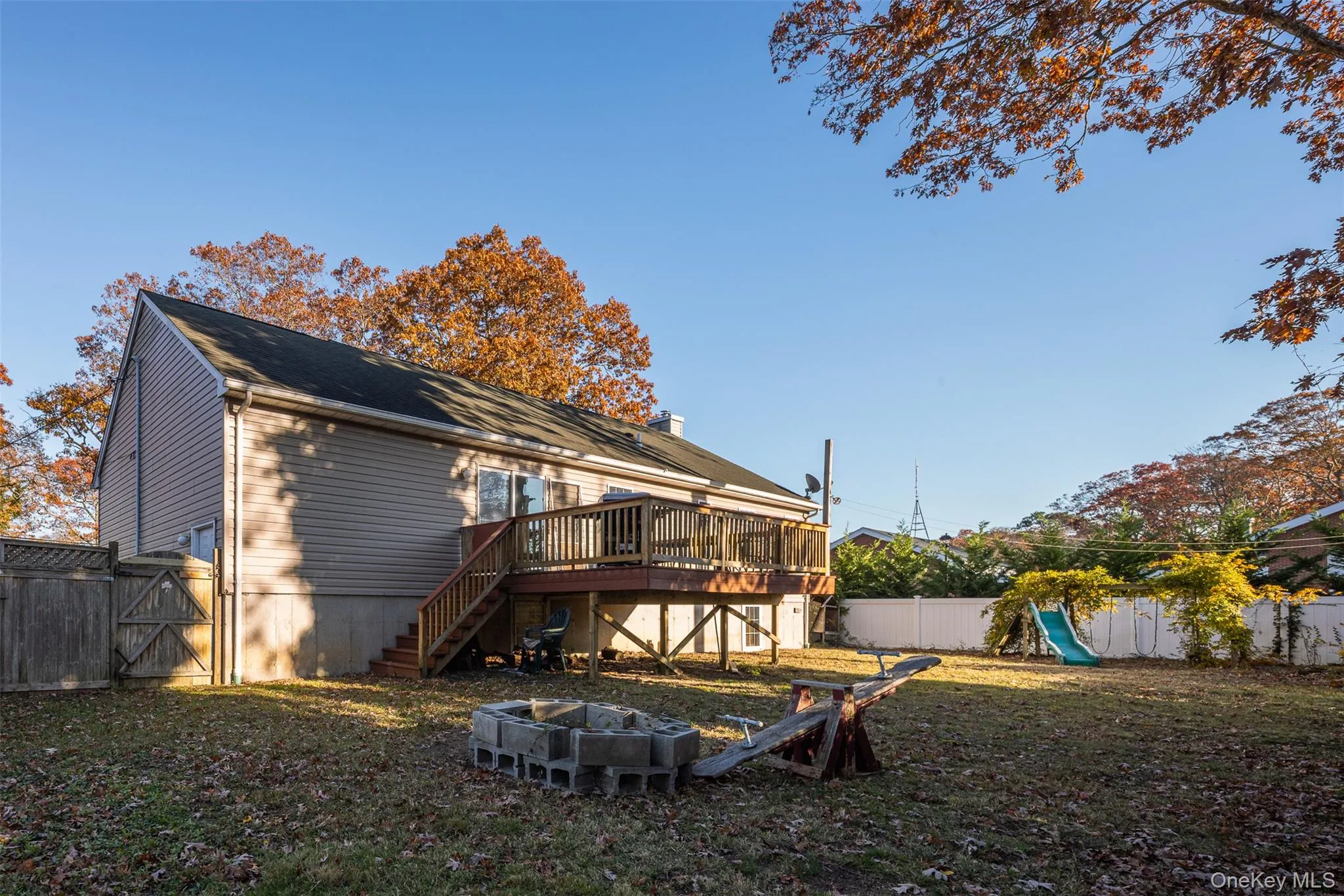 Back of house featuring a fenced backyard, stairway, a gate, a wooden deck, and an outdoor fire pit Back of house featuring a fenced backyard, stairway, a gate, a wooden deck, and an outdoor fire pit