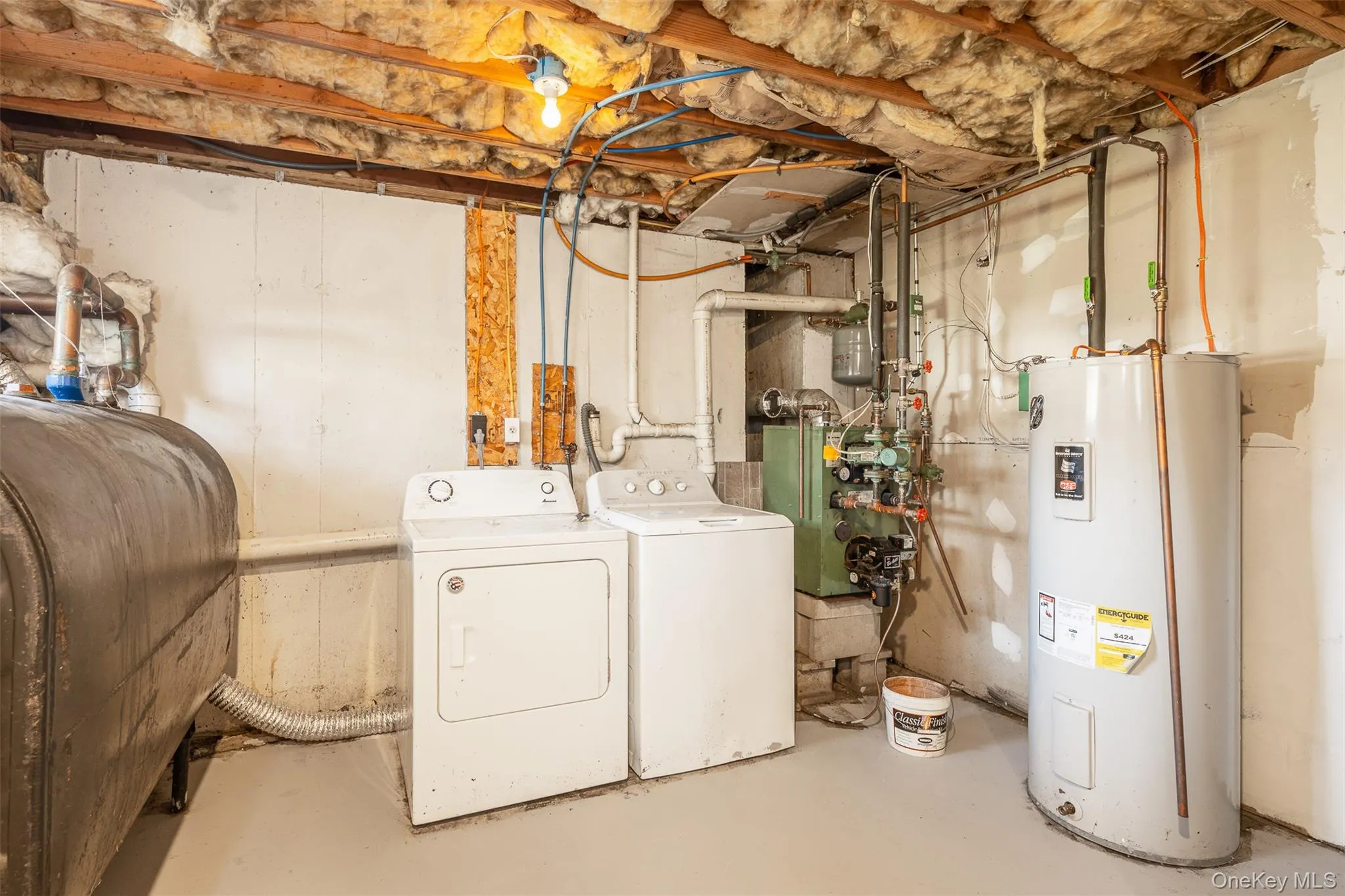 Washroom with concrete floors, oil tank, water heater, washing machine and clothes dryer, and a heating unit Washroom with concrete floors, oil tank, water heater, washing machine and clothes dryer, and a heating unit