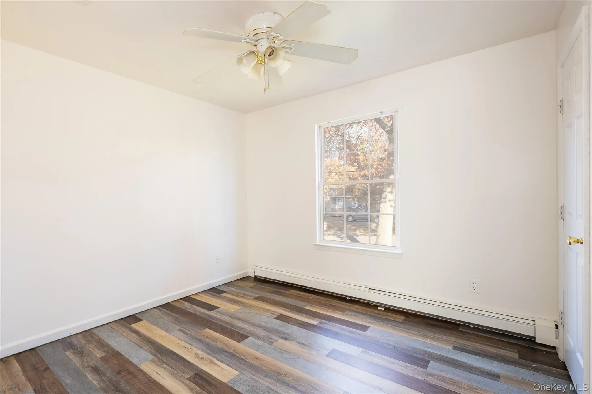 Empty room featuring a baseboard heating unit, dark wood finished floors, and a ceiling fan Empty room featuring a baseboard heating unit, dark wood finished floors, and a ceiling fan