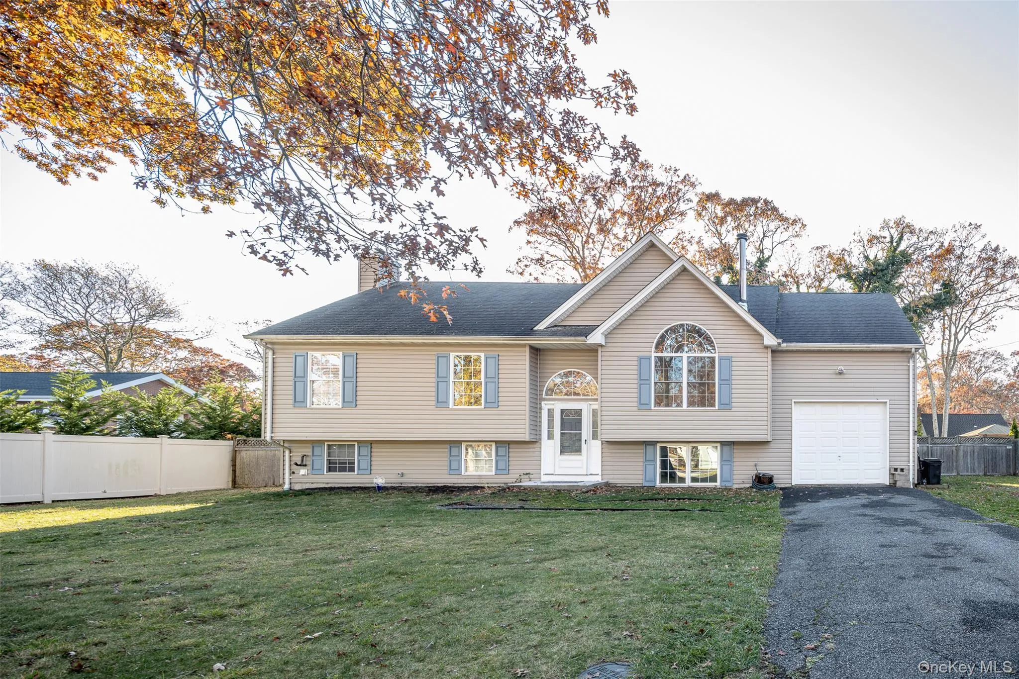 Split foyer home featuring a chimney, asphalt driveway, and an attached garage Split foyer home featuring a chimney, asphalt driveway, and an attached garage