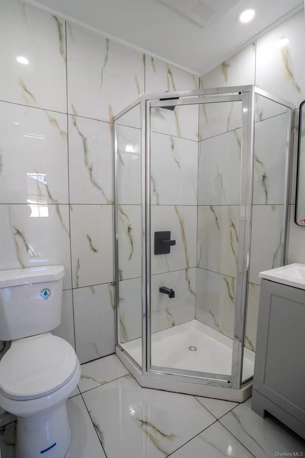 Bathroom featuring a marble finish shower, vanity, tile walls, and recessed lighting Bathroom featuring a marble finish shower, vanity, tile walls, and recessed lighting