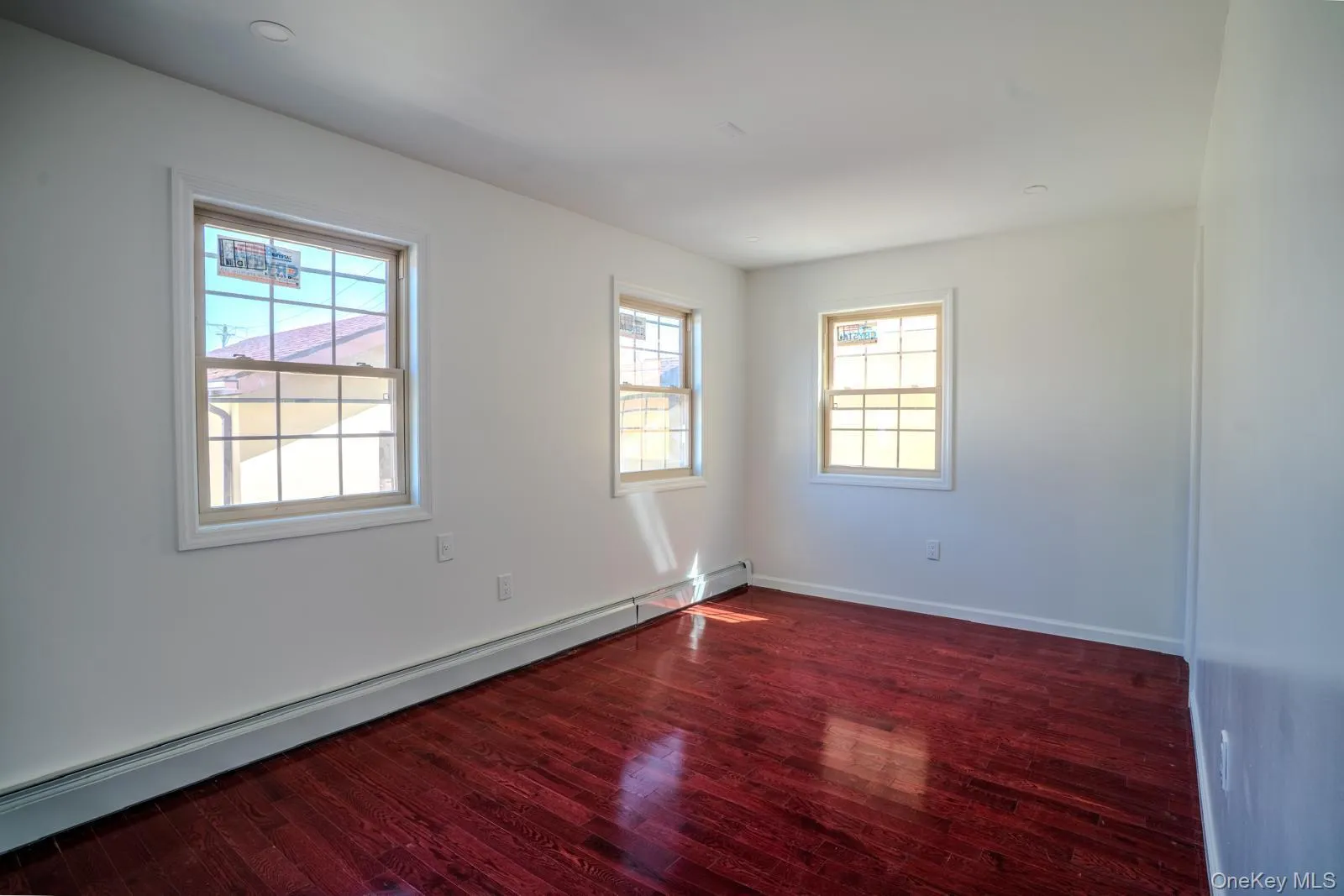 Spare room featuring a baseboard heating unit and dark wood-style floors Spare room featuring a baseboard heating unit and dark wood-style floors