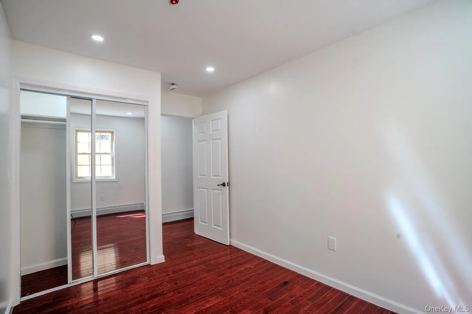 Unfurnished bedroom featuring dark wood-style floors, a closet, recessed lighting, and baseboard heating Unfurnished bedroom featuring dark wood-style floors, a closet, recessed lighting, and baseboard heating