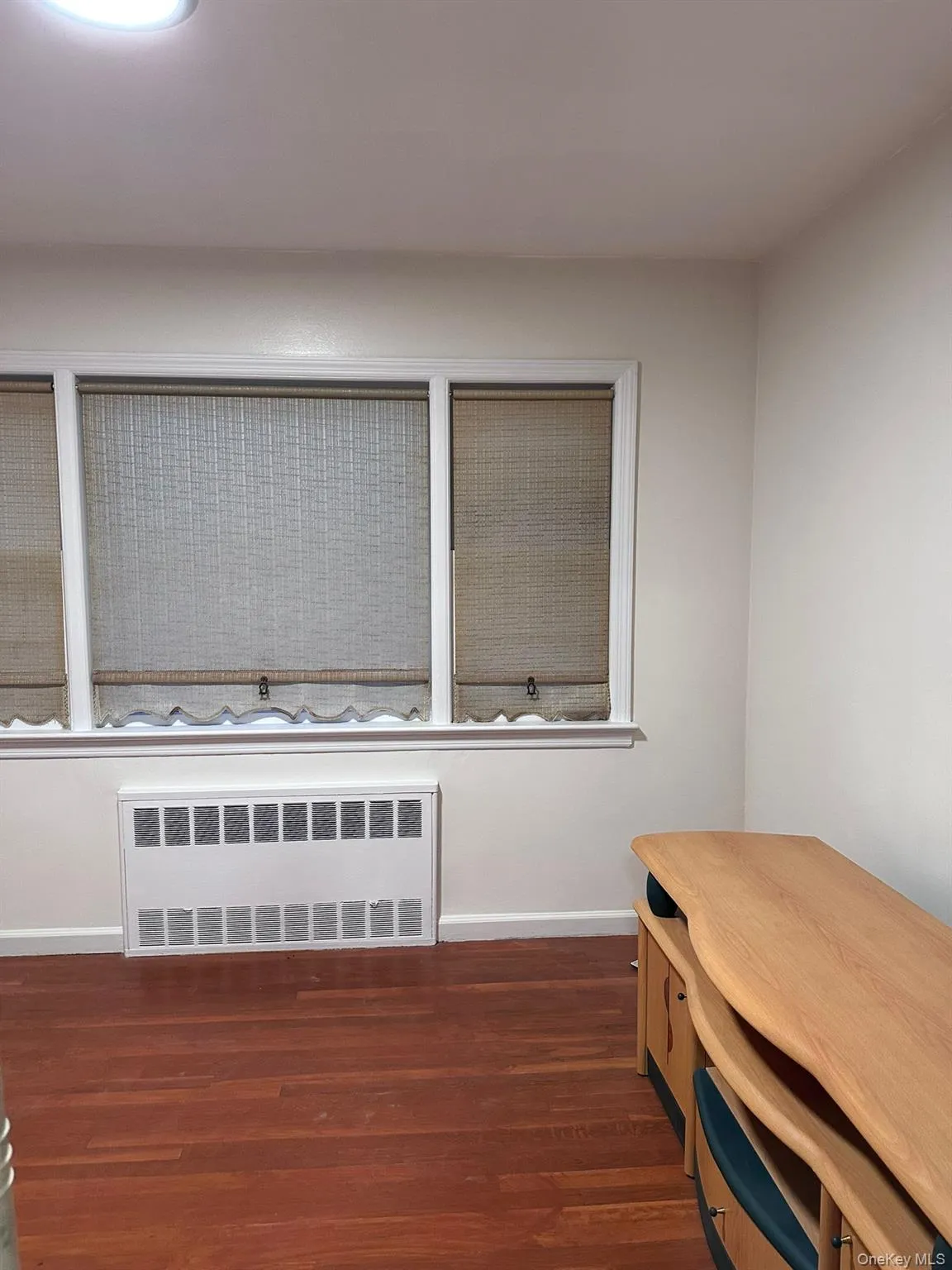 Office space with radiator heating unit and dark wood-style floors Office space with radiator heating unit and dark wood-style floors