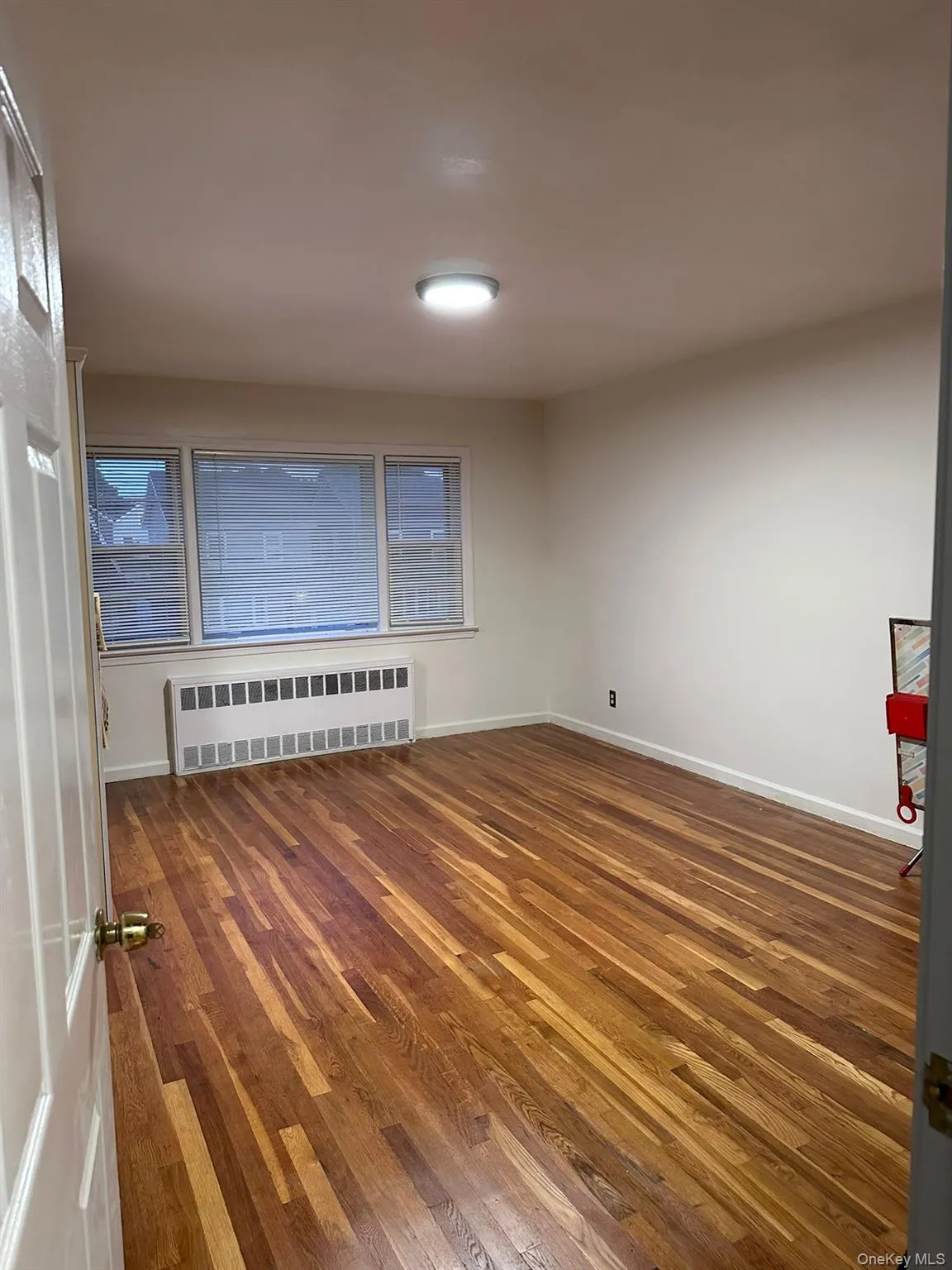 Empty room featuring dark wood finished floors and radiator Empty room featuring dark wood finished floors and radiator