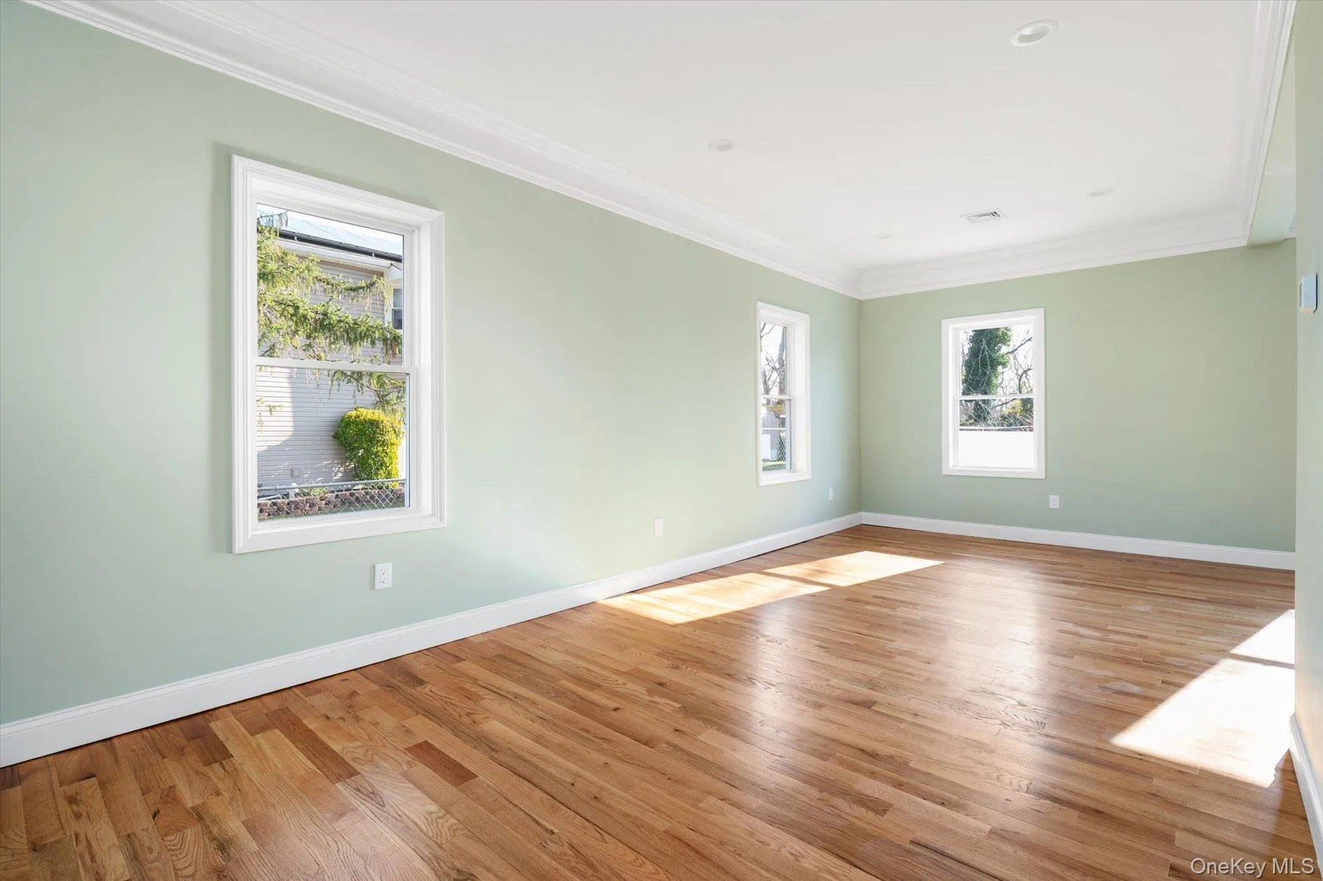 Unfurnished room featuring ornamental molding and light wood-type flooring Unfurnished room featuring ornamental molding and light wood-type flooring