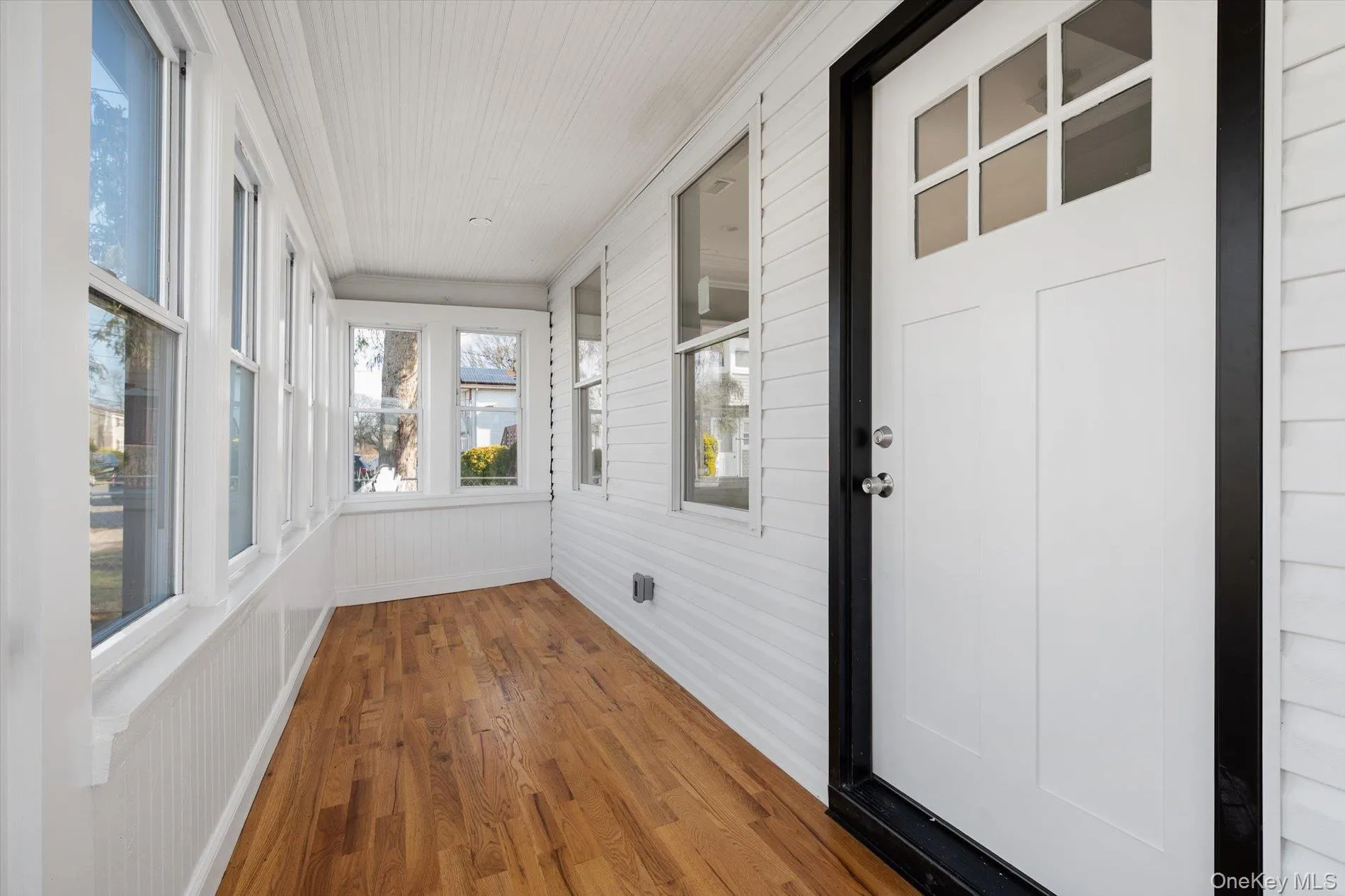 Unfurnished sunroom with wood finished floors, ornamental molding, and wooden walls Unfurnished sunroom with wood finished floors, ornamental molding, and wooden walls