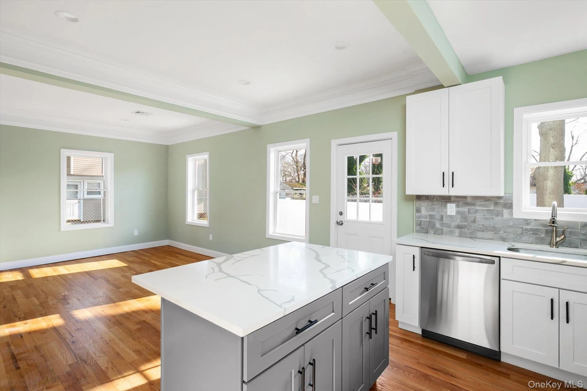Kitchen featuring white cabinetry, stainless steel dishwasher, light stone counters, gray cabinetry, and crown molding Kitchen featuring white cabinetry, stainless steel dishwasher, light stone counters, gray cabinetry, and crown molding