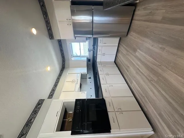 Kitchen with dark countertops, oven, a textured ceiling, fridge, and light wood finished floors Kitchen with dark countertops, oven, a textured ceiling, fridge, and light wood finished floors