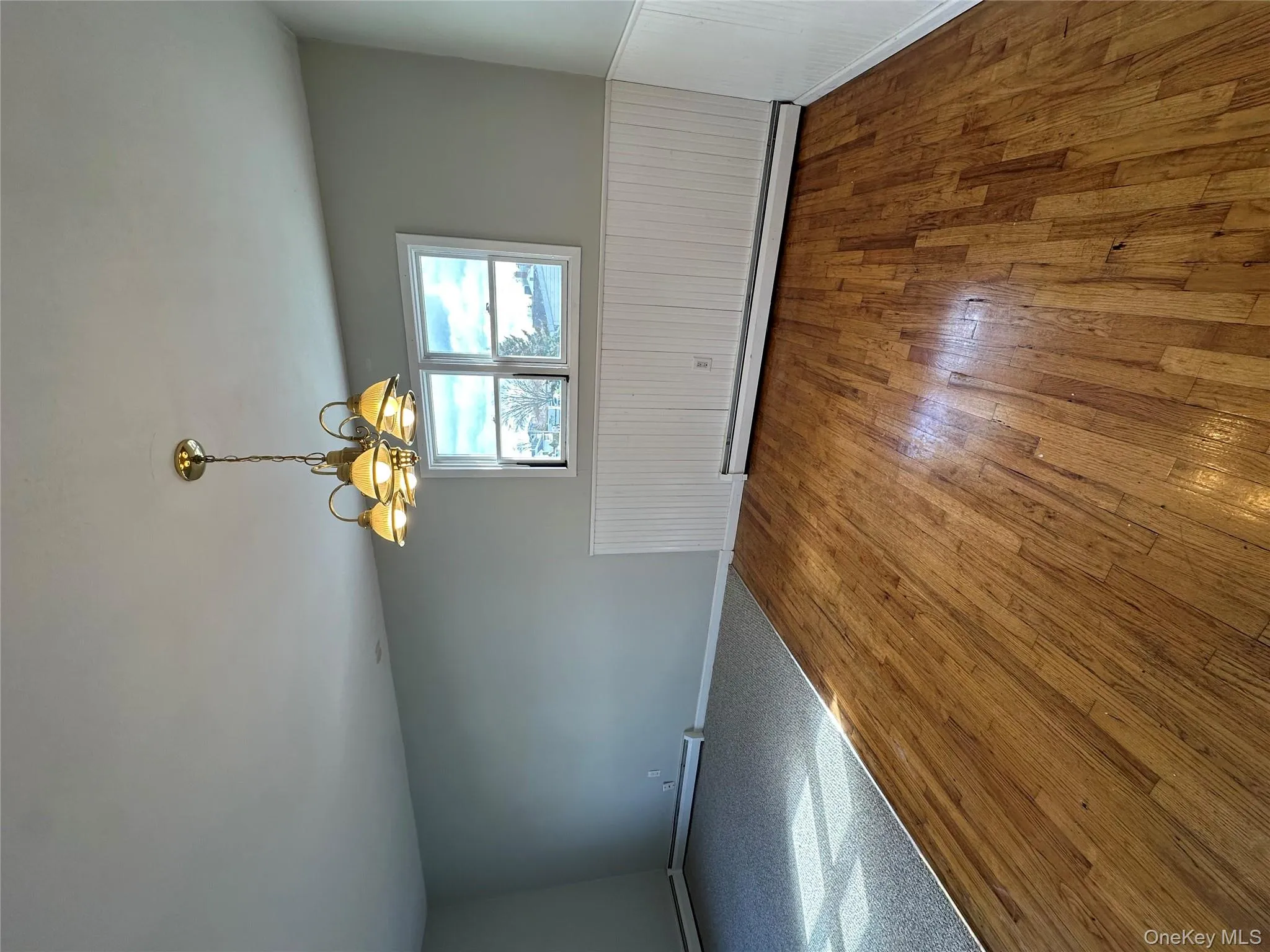 Empty room with hardwood / wood-style floors, a baseboard heating unit, a chandelier, and wainscoting Empty room with hardwood / wood-style floors, a baseboard heating unit, a chandelier, and wainscoting