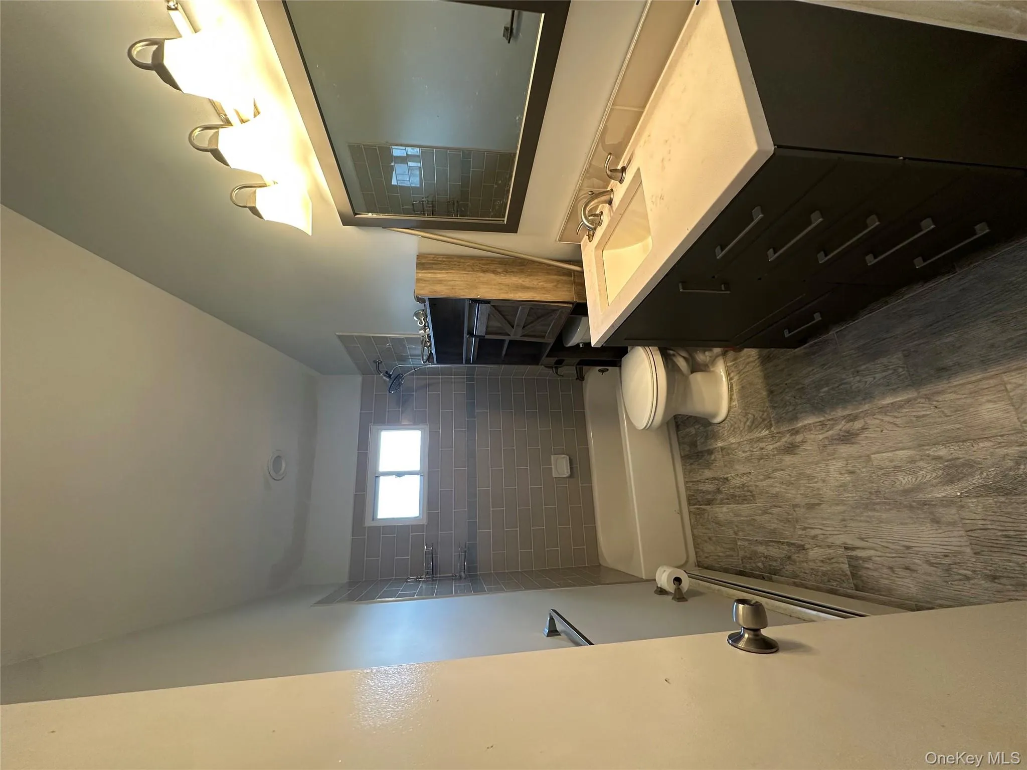 Full bath featuring vanity, dark wood-style flooring, bathing tub / shower combination, and a baseboard radiator Full bath featuring vanity, dark wood-style flooring, bathing tub / shower combination, and a baseboard radiator