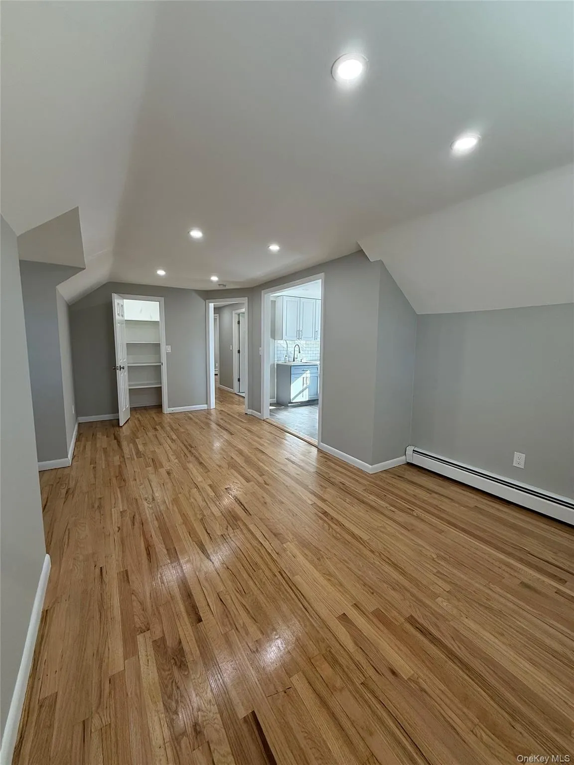 Bonus room featuring a baseboard heating unit, recessed lighting, light wood-style floors, and lofted ceiling Bonus room featuring a baseboard heating unit, recessed lighting, light wood-style floors, and lofted ceiling