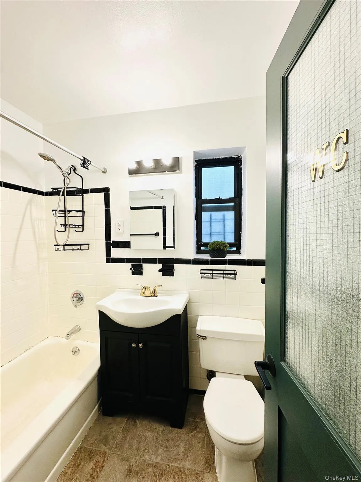 Full bath featuring vanity, tile walls, shower / tub combination, and wainscoting Full bath featuring vanity, tile walls, shower / tub combination, and wainscoting