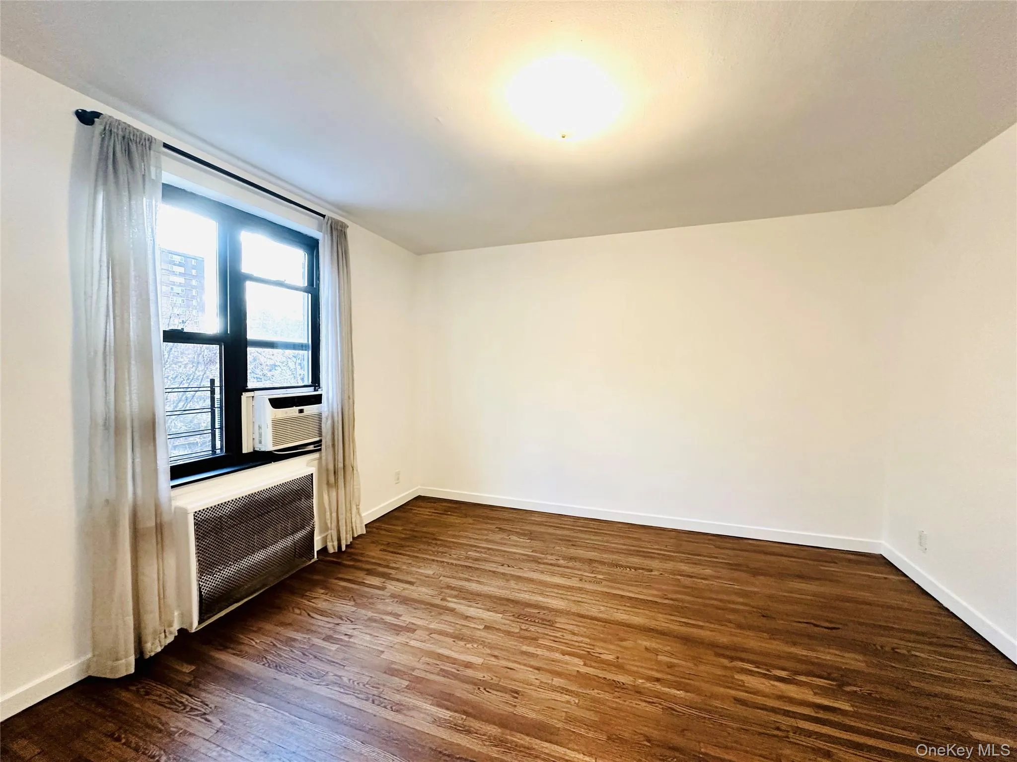 Unfurnished room with dark wood-style floors and baseboards Unfurnished room with dark wood-style floors and baseboards