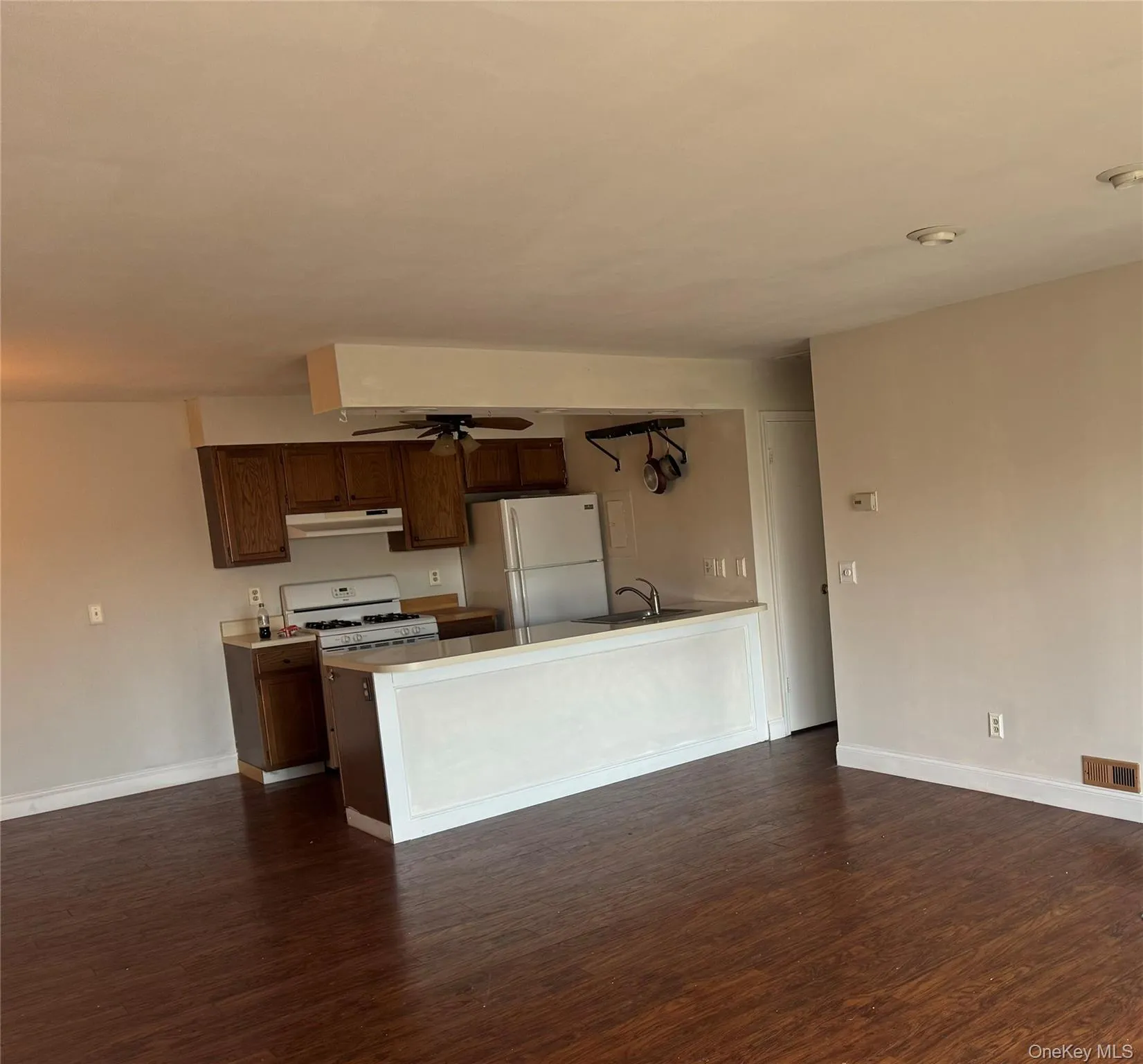 Kitchen with white appliances, dark wood finished floors, a peninsula, and dark brown cabinets Kitchen with white appliances, dark wood finished floors, a peninsula, and dark brown cabinets