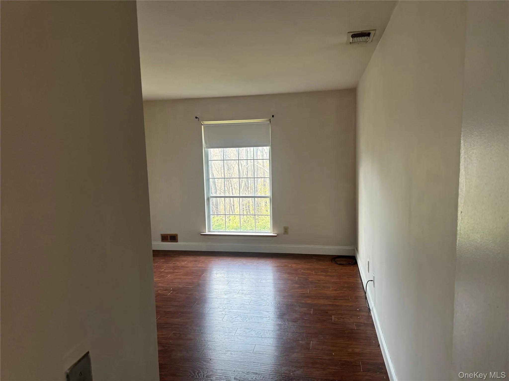 Unfurnished room with baseboards and dark wood-style flooring Unfurnished room with baseboards and dark wood-style flooring