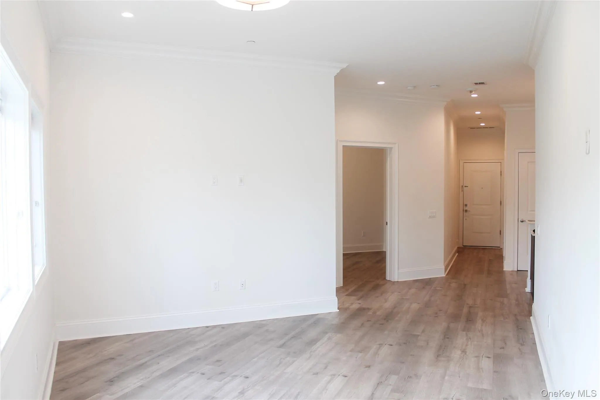 Empty room with ornamental molding, light wood finished floors, and recessed lighting Empty room with ornamental molding, light wood finished floors, and recessed lighting