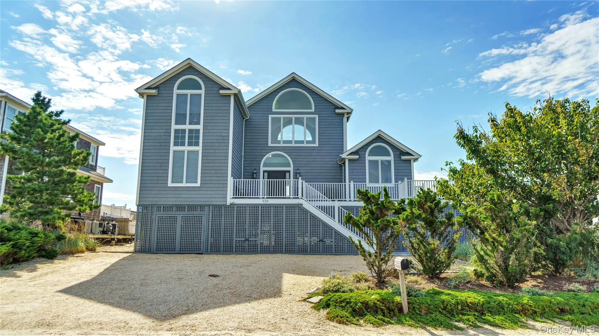 Beach home with stairs, driveway, a balcony, and a carport Beach home with stairs, driveway, a balcony, and a carport