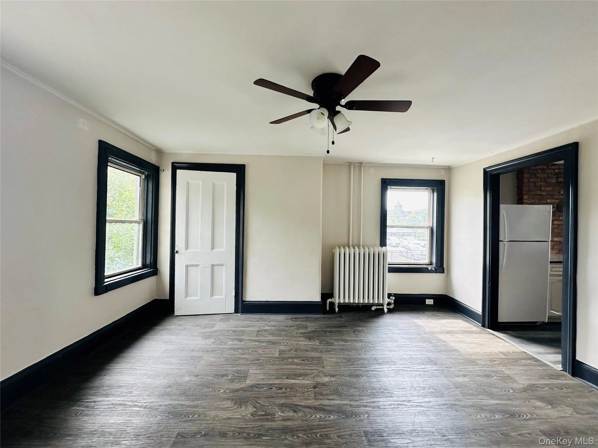 Unfurnished room featuring wood finished floors, radiator, and a ceiling fan Unfurnished room featuring wood finished floors, radiator, and a ceiling fan