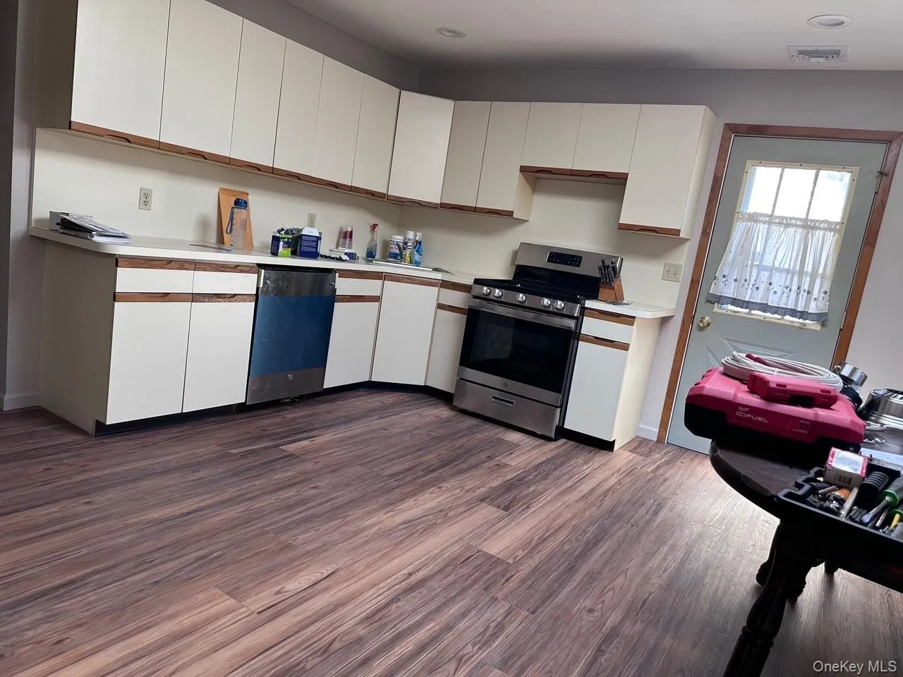 Kitchen with white cabinets, stainless steel range oven, light countertops, dark wood-type flooring, and dishwashing machine Kitchen with white cabinets, stainless steel range oven, light countertops, dark wood-type flooring, and dishwashing machine