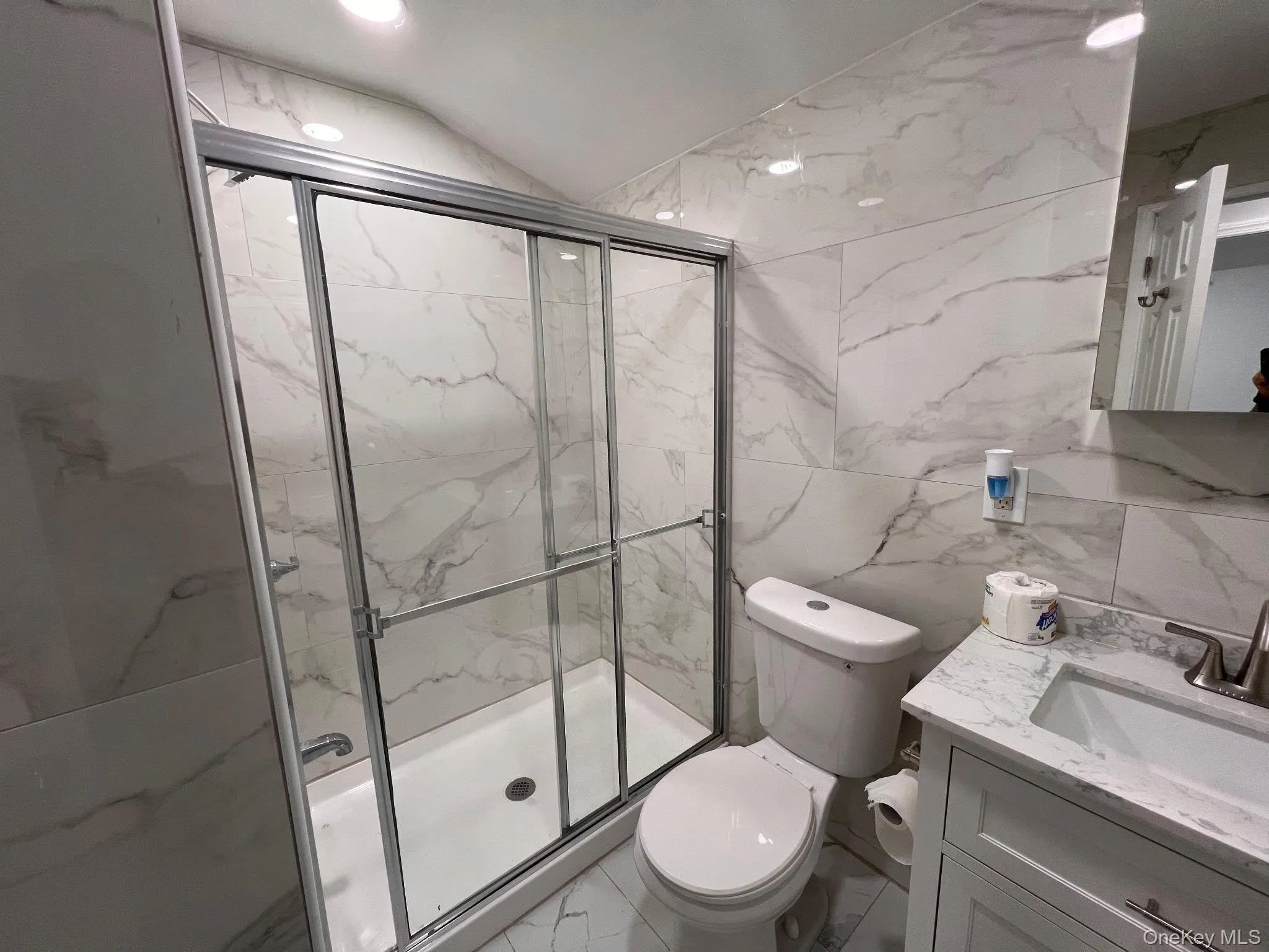 Bathroom with tile walls, lofted ceiling, vanity, a marble finish shower, and marble finish floors Bathroom with tile walls, lofted ceiling, vanity, a marble finish shower, and marble finish floors