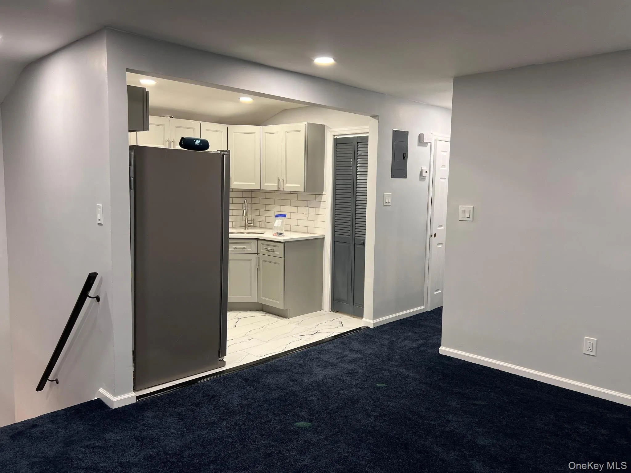 Kitchen with freestanding refrigerator, backsplash, light carpet, gray cabinetry, and recessed lighting Kitchen with freestanding refrigerator, backsplash, light carpet, gray cabinetry, and recessed lighting