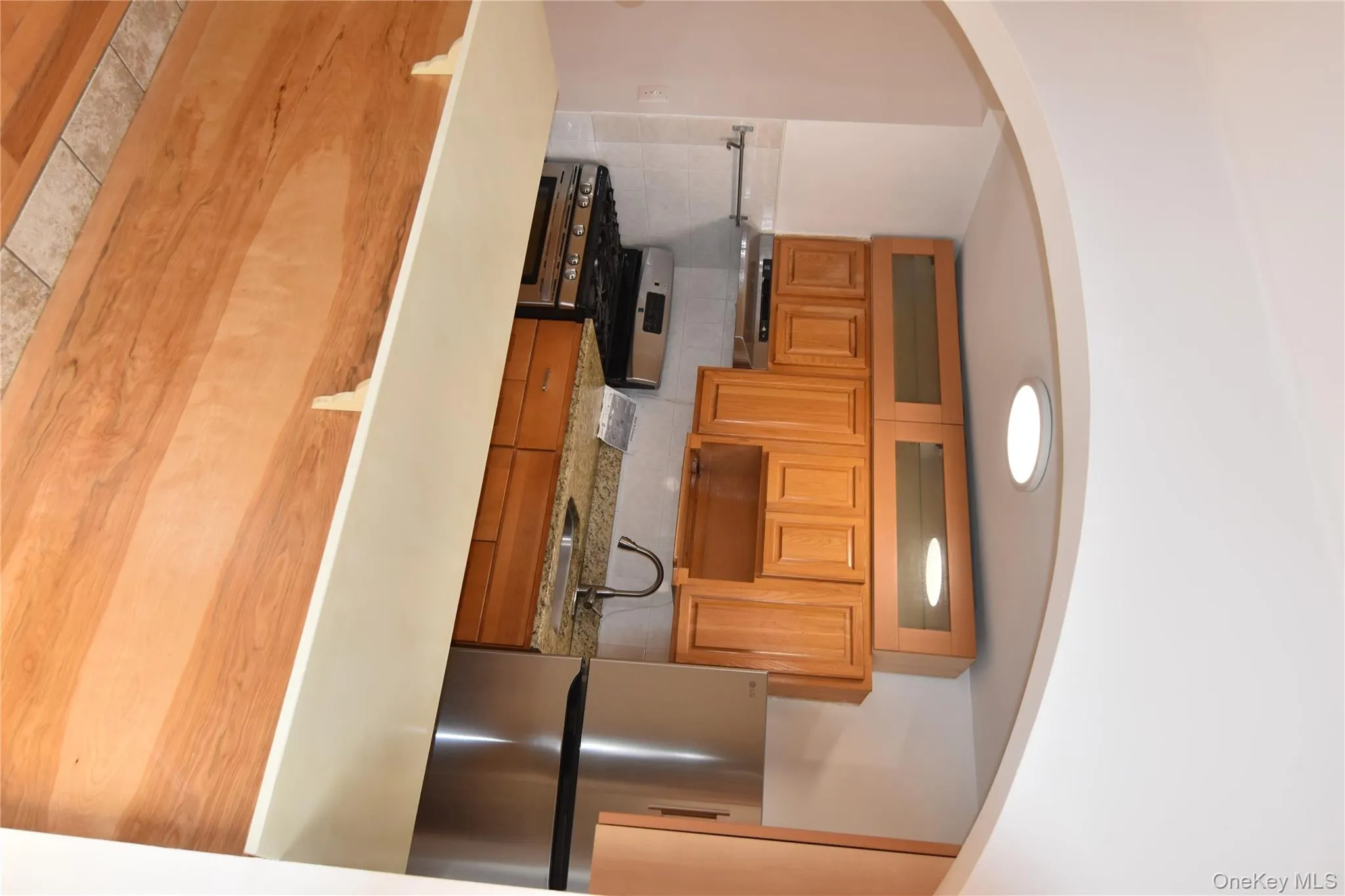 Kitchen with arched walkways, electric stove, fridge, light countertops, and backsplash Kitchen with arched walkways, electric stove, fridge, light countertops, and backsplash