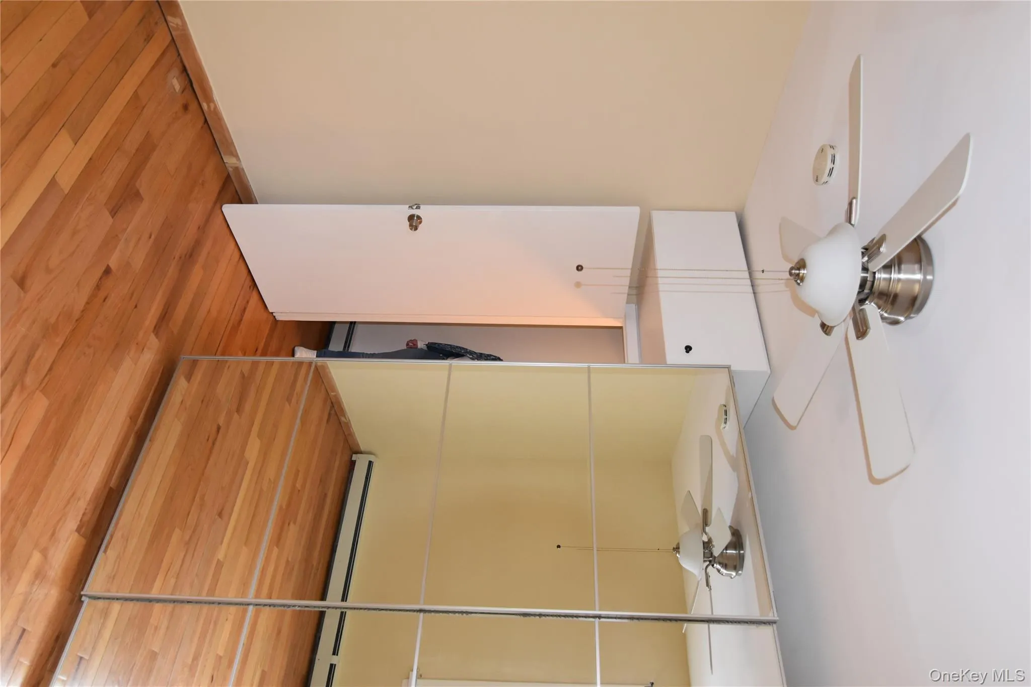 Spare room featuring ceiling fan, light wood-style flooring, and a baseboard radiator Spare room featuring ceiling fan, light wood-style flooring, and a baseboard radiator