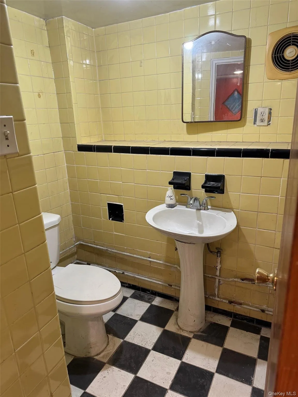 Half bathroom with tile walls and dark floors Half bathroom with tile walls and dark floors