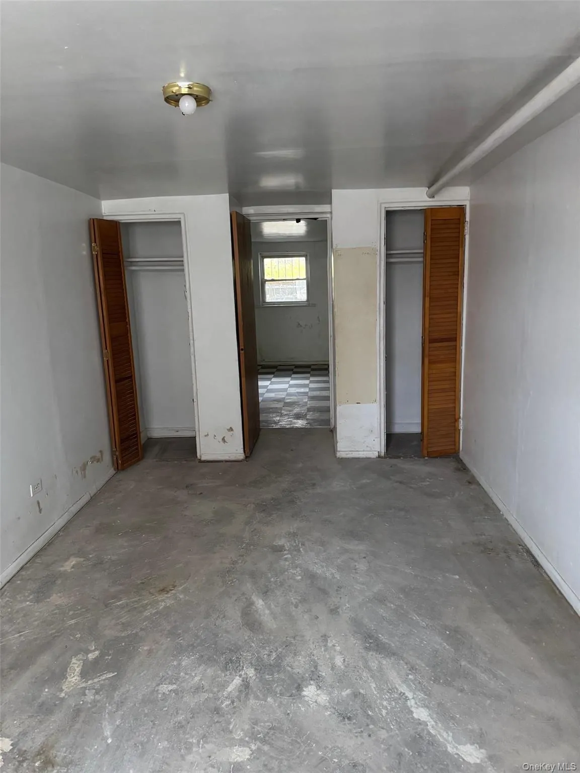 Unfurnished bedroom featuring multiple closets and concrete flooring Unfurnished bedroom featuring multiple closets and concrete flooring