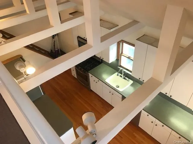 Kitchen featuring white cabinets, light wood-style flooring, a towering ceiling, and gas range Kitchen featuring white cabinets, light wood-style flooring, a towering ceiling, and gas range