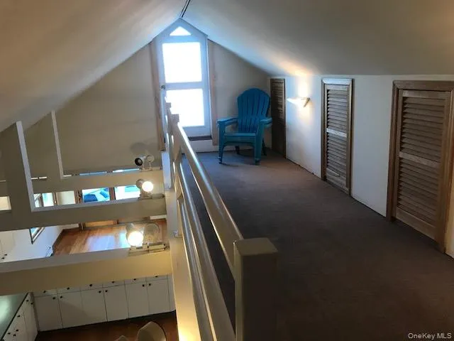 Bedroom featuring vaulted ceiling, two closets, and dark colored carpet Bedroom featuring vaulted ceiling, two closets, and dark colored carpet