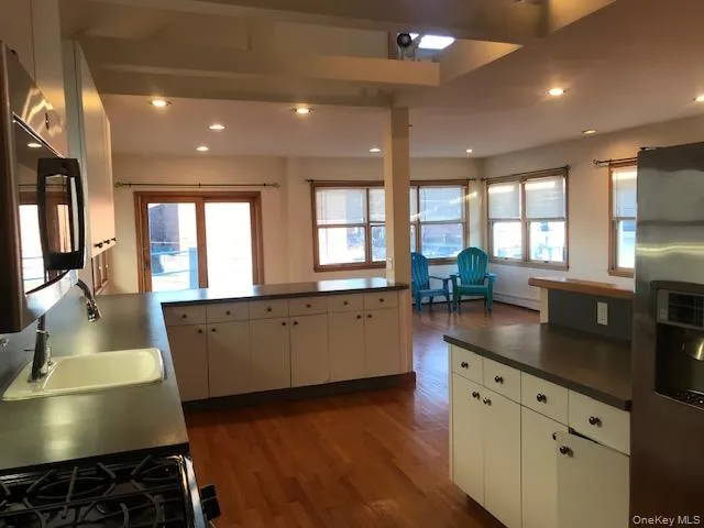 Kitchen featuring a peninsula, dark wood finished floors, stainless steel appliances, recessed lighting, and dark countertops Kitchen featuring a peninsula, dark wood finished floors, stainless steel appliances, recessed lighting, and dark countertops