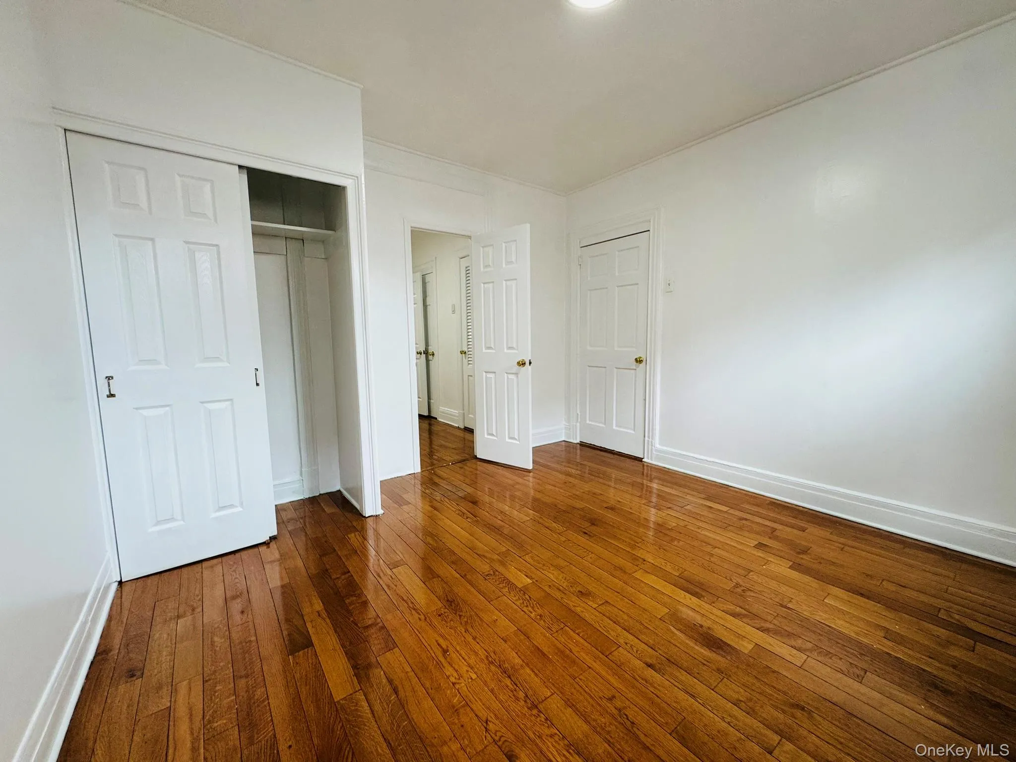 Unfurnished bedroom featuring dark wood-type flooring and a closet Unfurnished bedroom featuring dark wood-type flooring and a closet