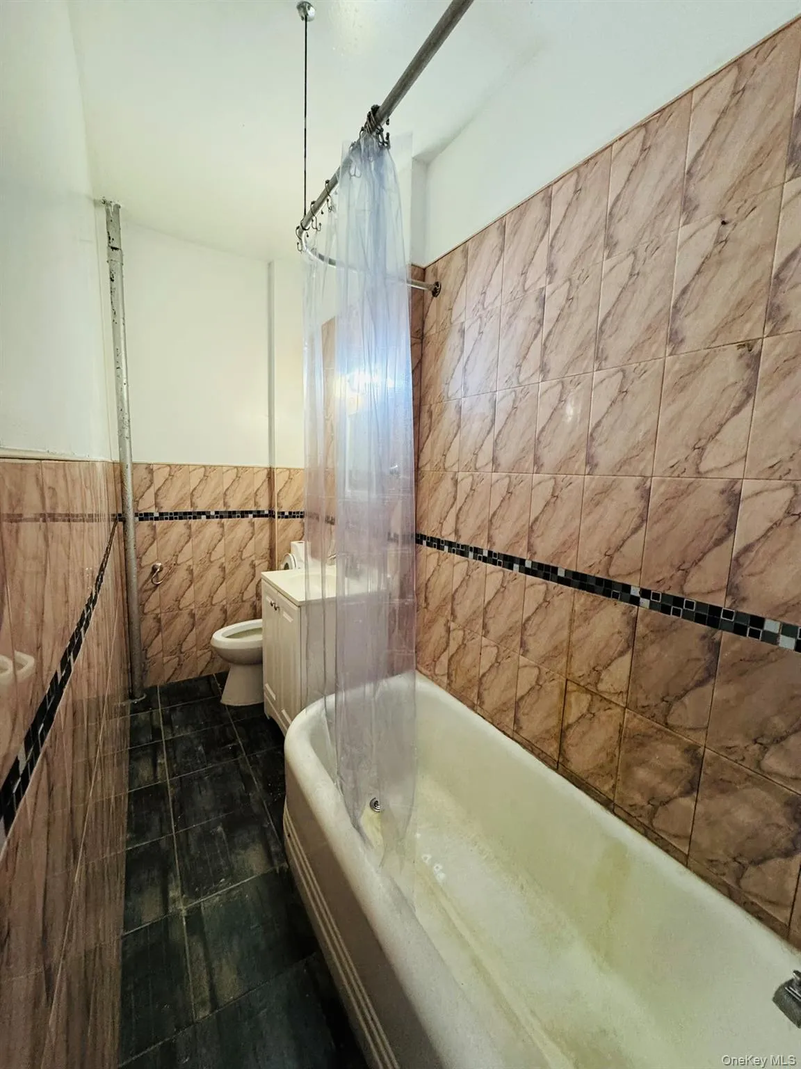 Bathroom featuring tile walls, shower / bath combo, and wainscoting Bathroom featuring tile walls, shower / bath combo, and wainscoting