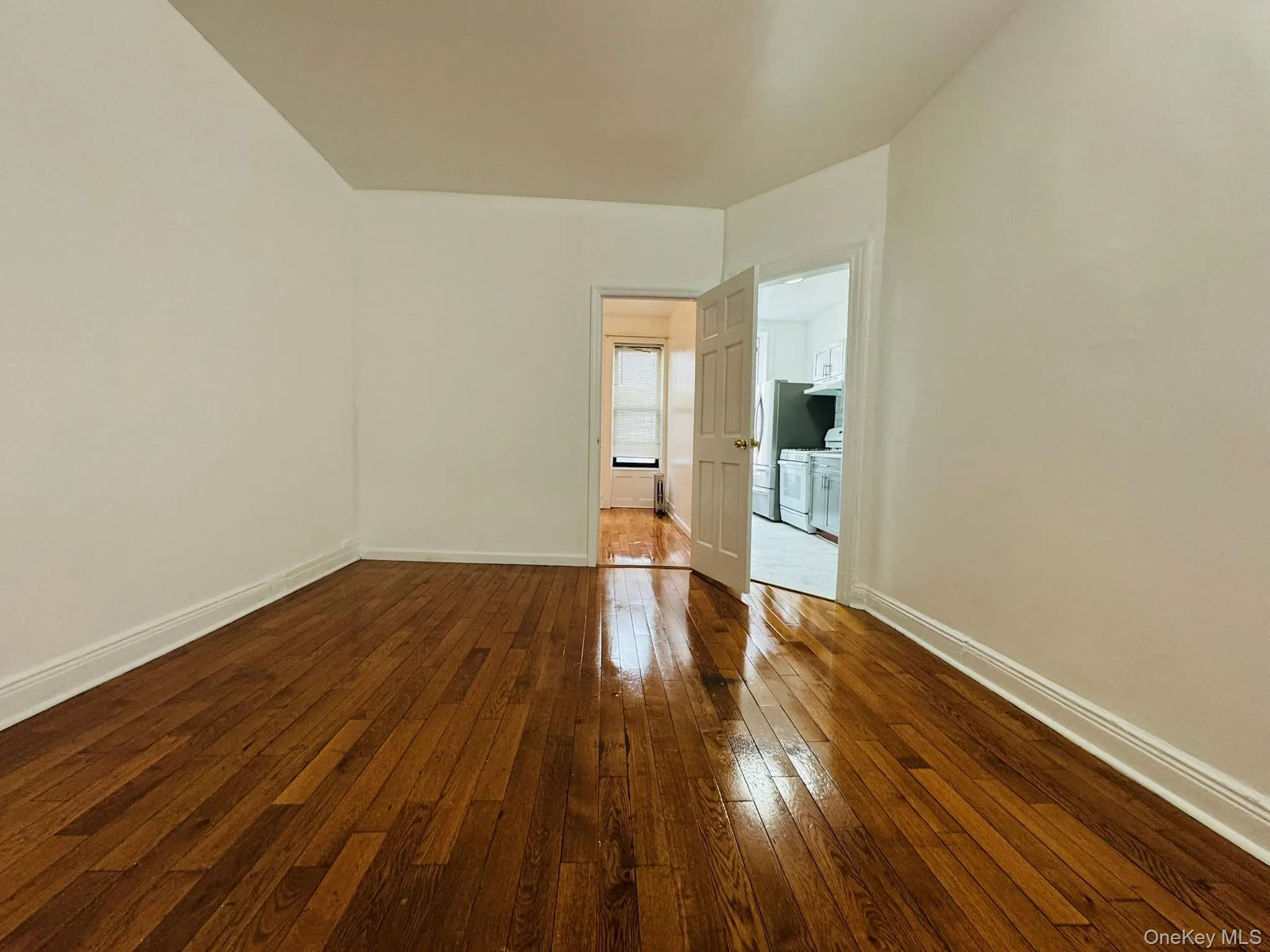 Empty room with dark wood-type flooring and baseboards Empty room with dark wood-type flooring and baseboards