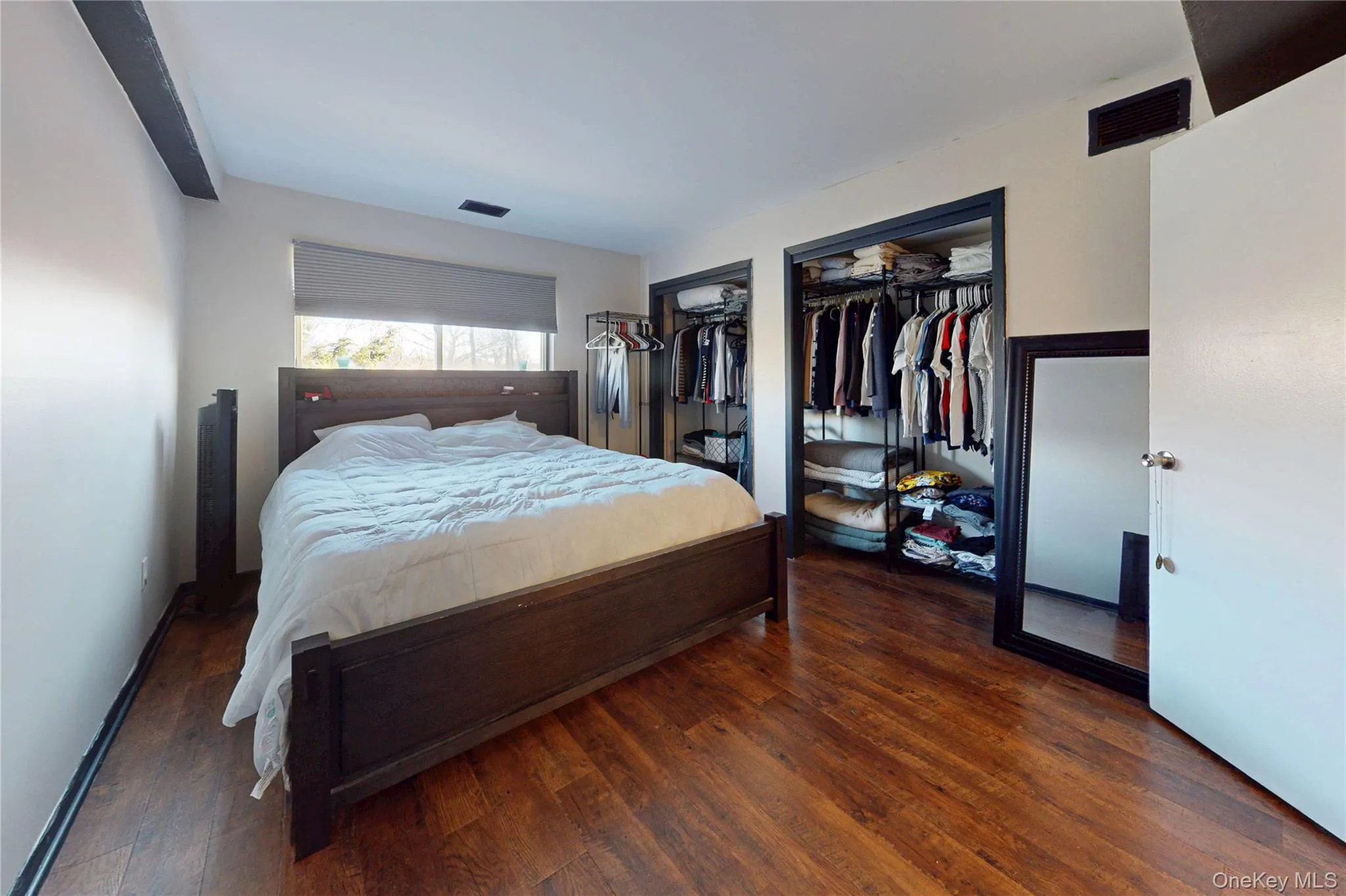 Bedroom featuring multiple closets and luxury laminate floors Bedroom featuring multiple closets and luxury laminate floors