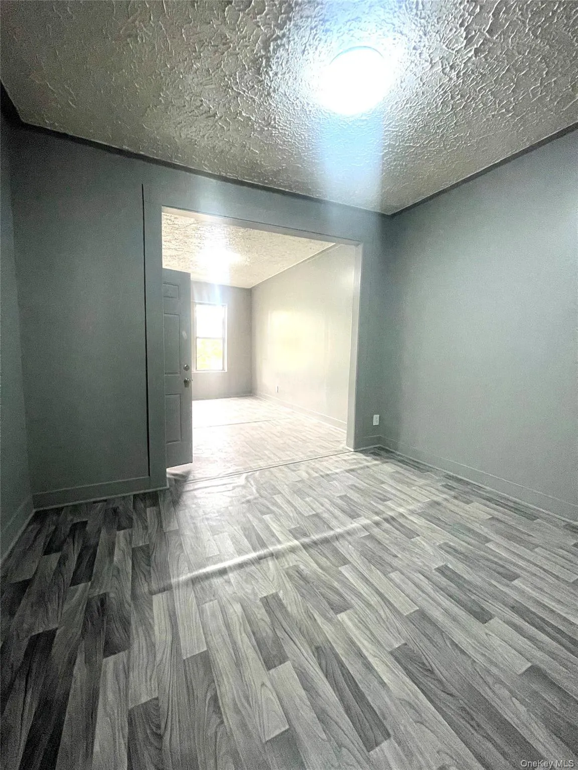 Unfurnished room with wood finished floors and a textured ceiling Unfurnished room with wood finished floors and a textured ceiling