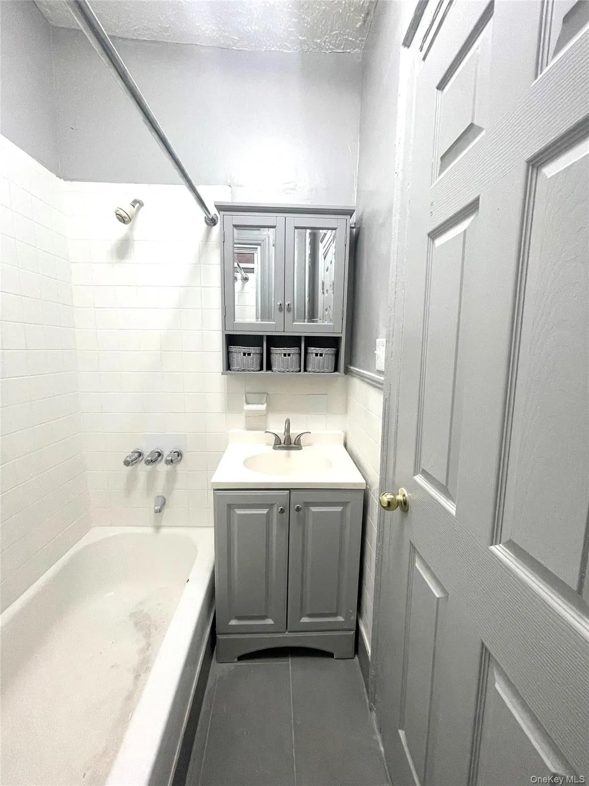 Bathroom with vanity, bathtub / shower combination, a textured ceiling, and dark tile patterned floors Bathroom with vanity, bathtub / shower combination, a textured ceiling, and dark tile patterned floors