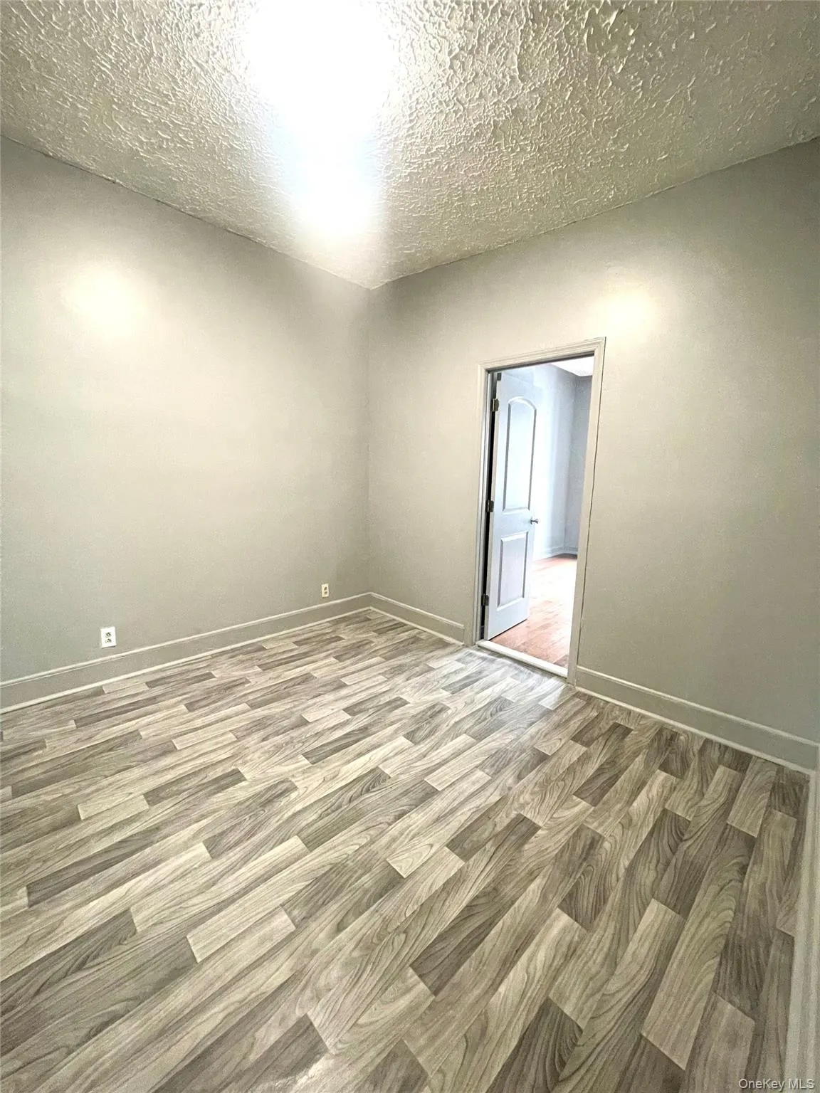 Empty room with wood finished floors and a textured ceiling Empty room with wood finished floors and a textured ceiling