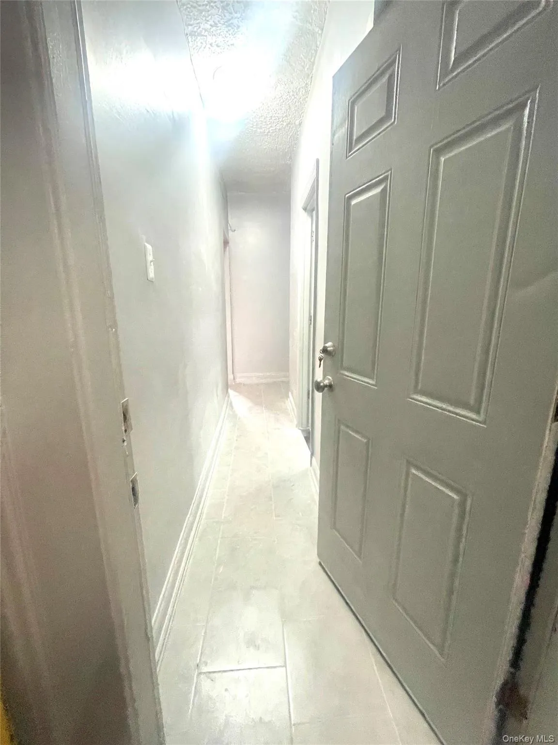Hallway with a textured ceiling and light tile patterned floors Hallway with a textured ceiling and light tile patterned floors