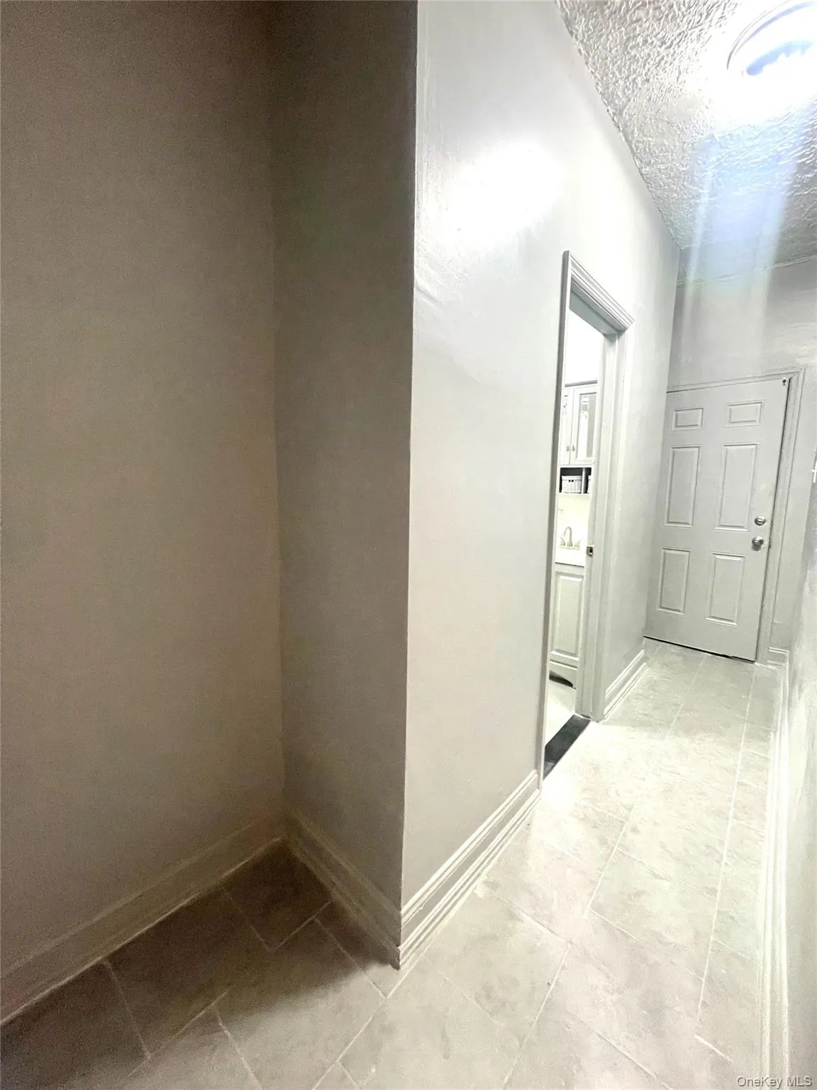 Hallway with a textured ceiling and light tile patterned floors Hallway with a textured ceiling and light tile patterned floors