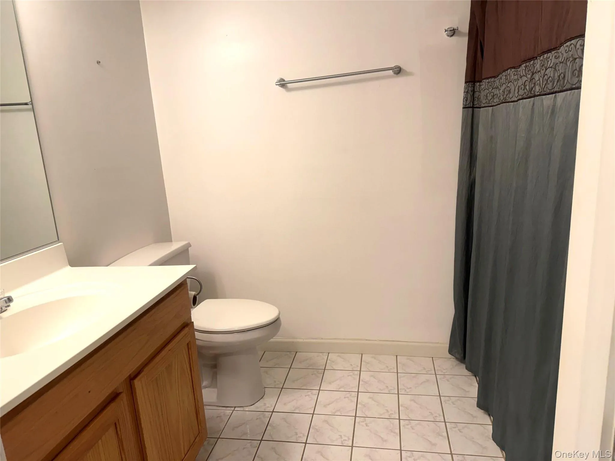 Bathroom featuring vanity, curtained shower, and light tile patterned floors Bathroom featuring vanity, curtained shower, and light tile patterned floors