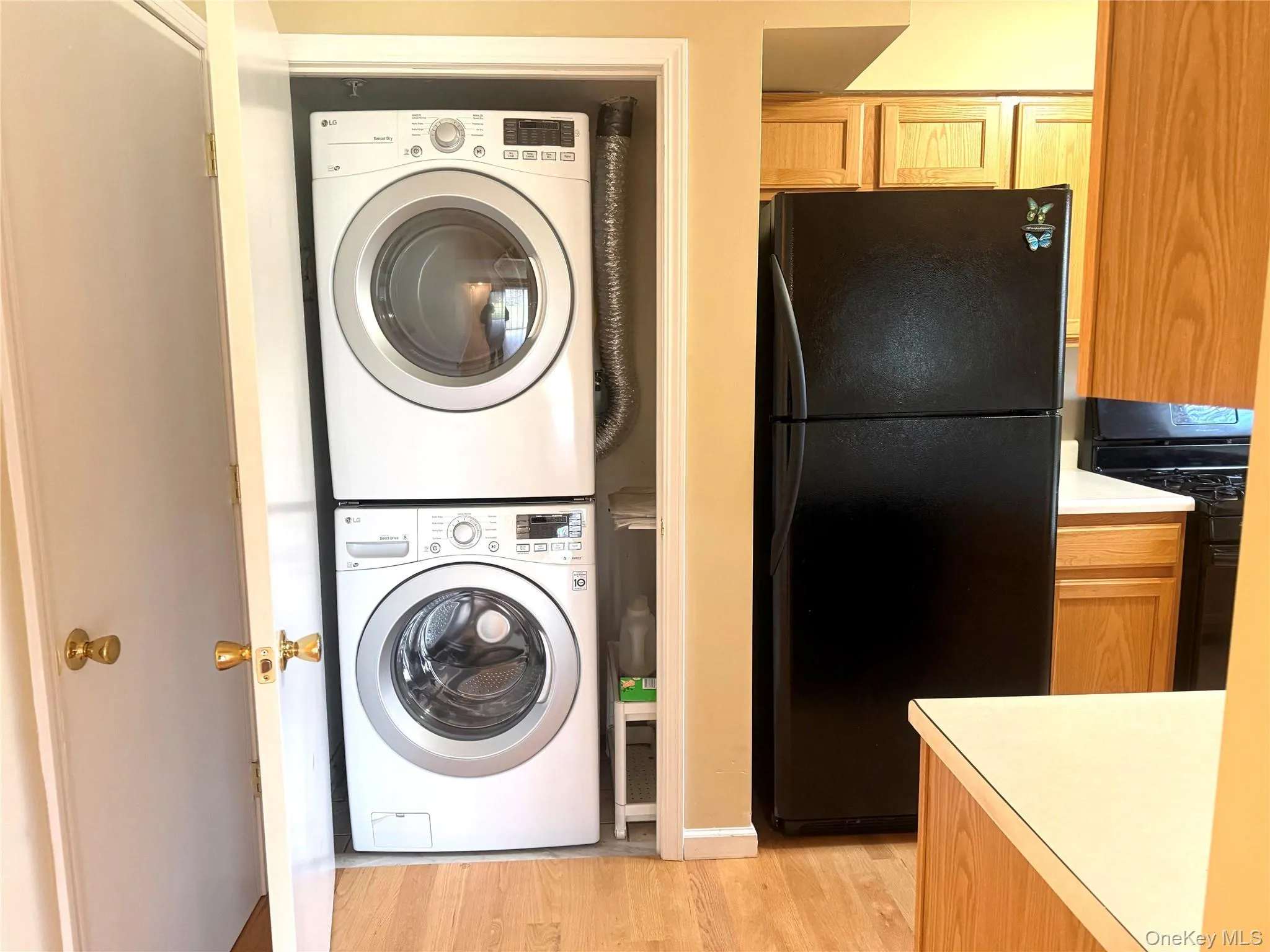 Laundry room featuring light wood finished floors and stacked washer / dryer Laundry room featuring light wood finished floors and stacked washer / dryer