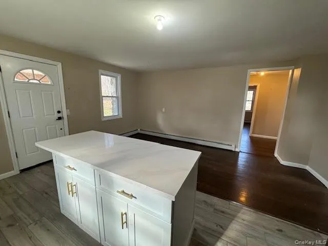 Kitchen with light countertops, light wood finished floors, white cabinetry, and a center island Kitchen with light countertops, light wood finished floors, white cabinetry, and a center island