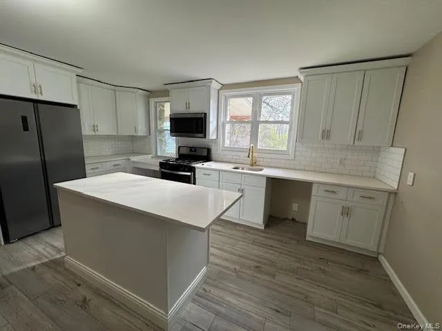Kitchen featuring appliances with stainless steel finishes, a kitchen island, and white cabinets Kitchen featuring appliances with stainless steel finishes, a kitchen island, and white cabinets