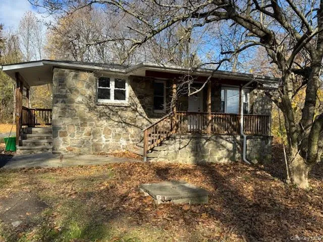 View of front of property with stone siding and a wooden deck View of front of property with stone siding and a wooden deck