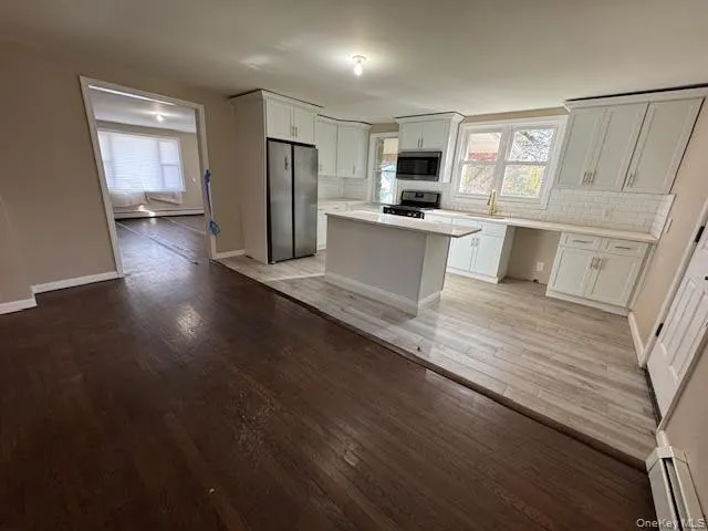 Eat in Kitchen with stainless steel appliances, decorative backsplash, light wood-style floors, white cabinetry, and a center island Eat in Kitchen with stainless steel appliances, decorative backsplash, light wood-style floors, white cabinetry, and a center island