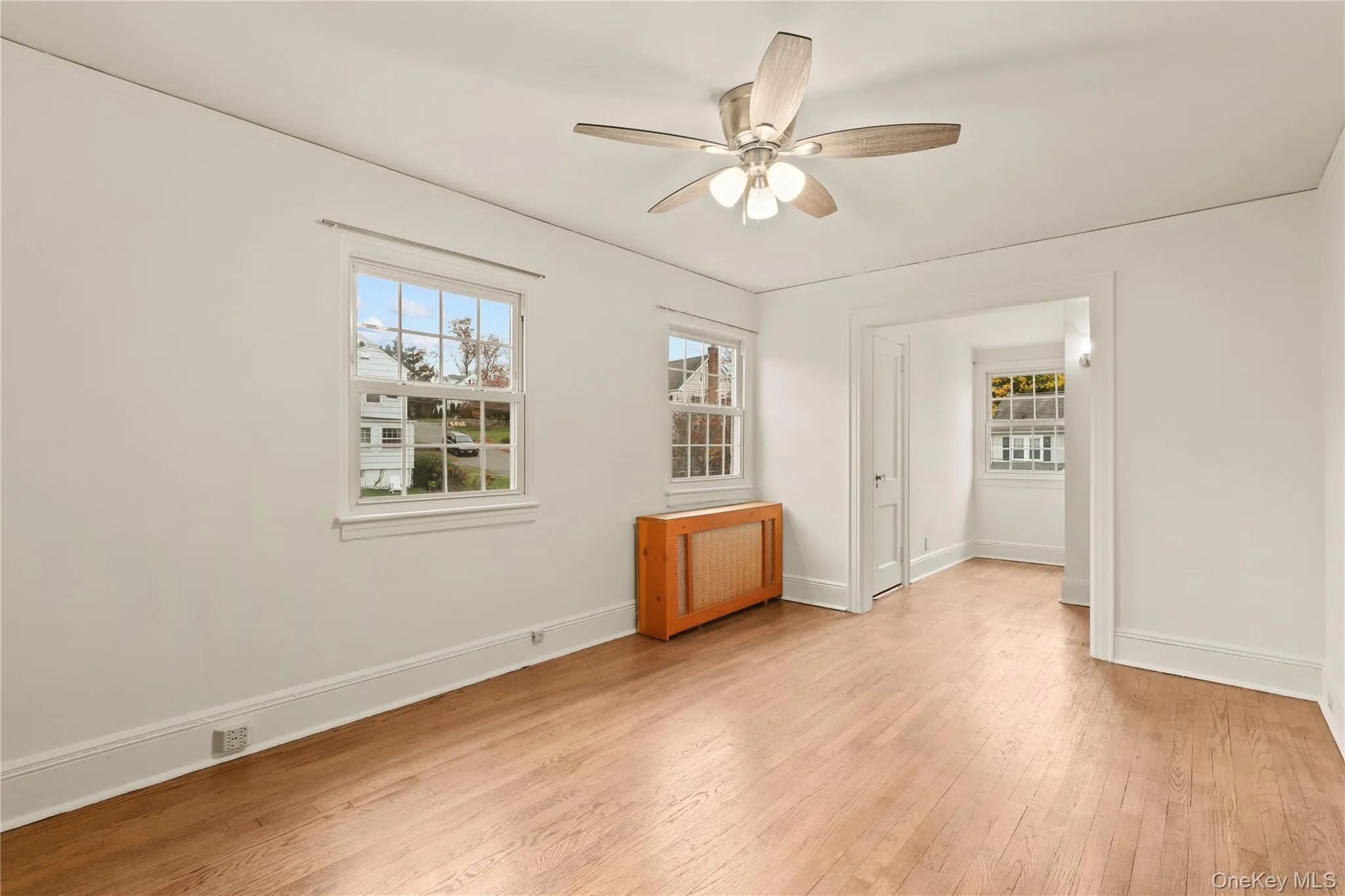 Unfurnished bedroom featuring light wood-style flooring, a ceiling fan, and radiator Unfurnished bedroom featuring light wood-style flooring, a ceiling fan, and radiator